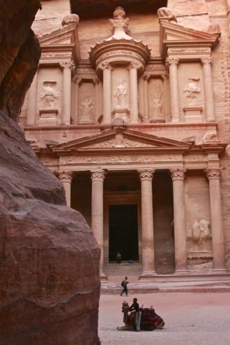 A vertical view of the Treasury building in Petra seen through the narrow rock walls of the Siq canyon.